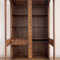 This beautiful art-deco arched glass and wood bookcase or curio cabinet is manufactured by the reputable B.P. John from Portland, Oregon. This piece is in such beautiful condition and the amazing arched doors and original brass hardware is a show-stopper for any style of home, office or commercial space.