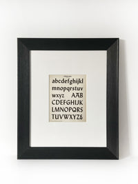 Lydian Bold - Vintage Industrial Font Alphabet Graphic Framed Art Framed in a modernized black frame with white mat. The alphabet fonts and numbers are featured on an antiqued page of type and lettering for typographers, letterers and designers published in 1950.