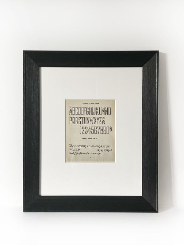 Agency Gothic Open Vintage Industrial Font Alphabet Graphic Framed Art Framed in a modernized black frame with white mat. The alphabet fonts and numbers are featured on an antiqued page of type and lettering for typographers, letterers and designers published in 1950. 