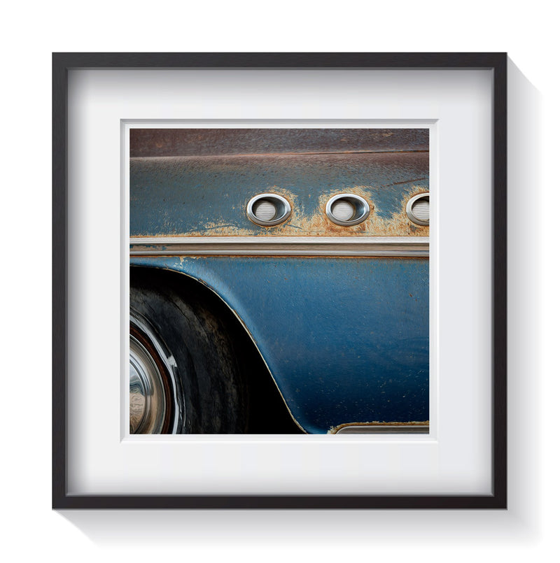 An old vintage patina blue car with three air vents on the side. Framed fine art classic car photography by Andrew Grant.   Framed wall art for your home, office, business, restaurant, bar, vacation house or hotel.