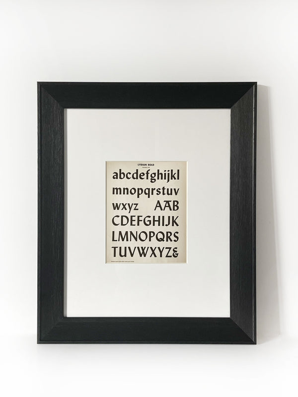 Lydian Bold - Vintage Industrial Font Alphabet Graphic Framed Art Framed in a modernized black frame with white mat. The alphabet fonts and numbers are featured on an antiqued page of type and lettering for typographers, letterers and designers published in 1950. 